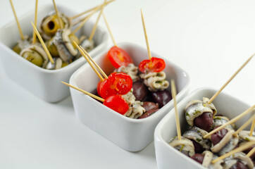 The traditional Spanish appetizers of olives, tomatoes and anchovies in a white ceramic bowls