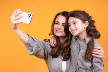 Beautiful woman and little daughter are photographed on the phone on a bright background