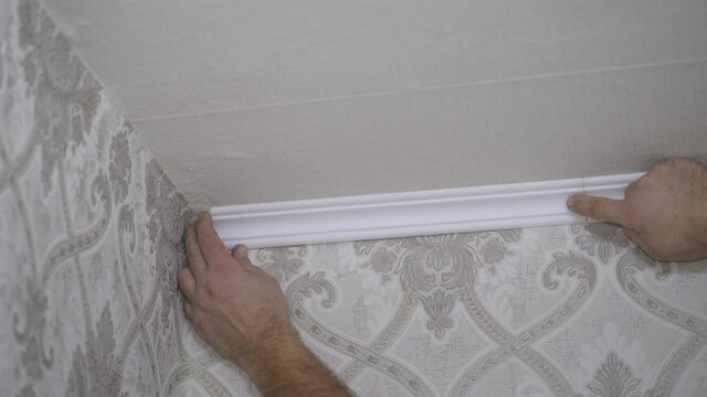 Installation of a ceiling skirting board on liquid nails to a ceiling, a wall.