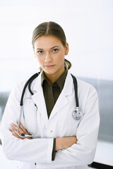 Woman-doctor standing with arms crossed and looking at camera. Perfect medical service in clinic. Medicine and healthcare