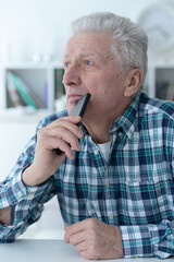 thoughtful senior man with smartphone