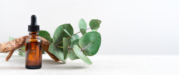 mockup glass bottle Essential oil or serum cosmetics with eucalyptus branches on textured white...