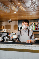 Submission of a Barista in a mask of delicious organic coffee in modern cafe during the pandemic.