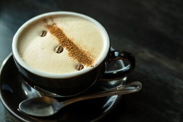 A cup of coffee with beautiful art from coffee beans on a wooden dark background.