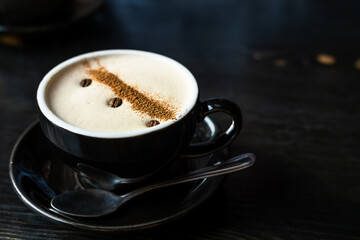 A cup of coffee with beautiful art from coffee beans on a wooden dark background.