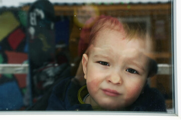 cute toddler baby boy close up portrait with flat nose agains the window