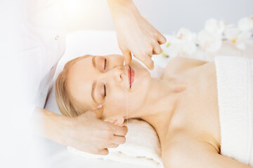 Fototapeta na wymiar Beautiful caucasian woman getting face depilation procedure. Beauty and Spa salon concept