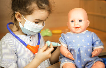 A girl with a doll plays doctor, makes a syringe inoculation in the hand. Vaccination, vaccination...