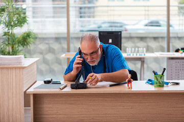 Old male doctor working in the clinic in telemedicine concept