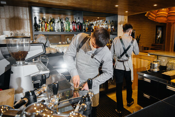 Two masked baristas prepare delicious coffee in the cafe bar. The work of restaurants and cafes during the pandemic.
