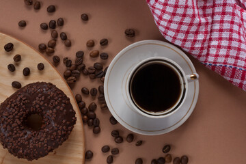 Fresh aromatic coffee in a mug with coffee beans and donut. Morning coffee. Coffee break.