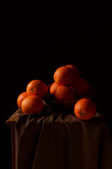 Pionowe ujęcie pomarańczy na brązowym obrusie i czarnym tle