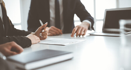 Unknown businessmen and woman sitting, working and discussing questions at meeting in modern office, close-up