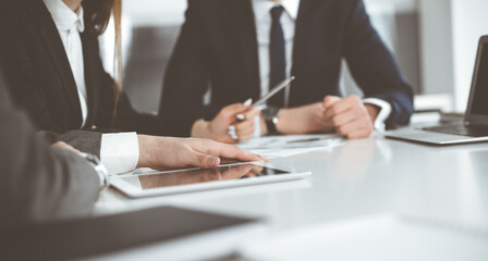 Unknown businessmen and woman sitting, working and discussing questions at meeting in modern office, close-up