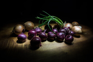 Vegetable concept. Onions in dark on wooden table. Selective focus