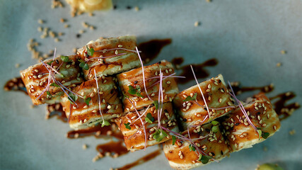 Top view of tasty fresh sushi roll set with unagi and sesame decorated and served on a plate
