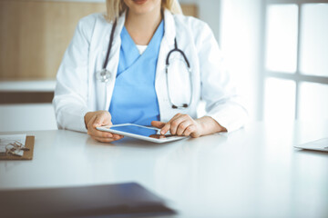 Unknown woman-doctor standing in clinic and using tablet pc, close-up. Data and best service in medicine and healthcare
