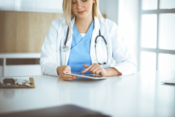 Unknown woman-doctor standing in clinic and using tablet pc, close-up. Data and best service in medicine and healthcare
