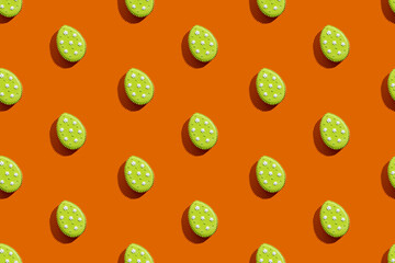Easter pattern. Festive seamless banner. Gingerbread pastry. Abstract background. Sweet cookies with green icing white flower decoration isolated on orange.