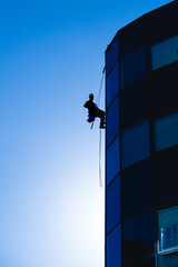 worker at heights washing the windows of the apartment building
