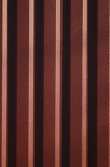Background with symmetrical brown straight lines. Trapezoidal sheet metal wall. Metal sheet metal...