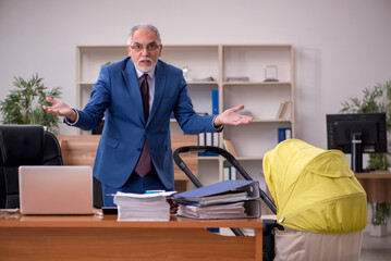 Aged businessman employee looking after newborn at workplace