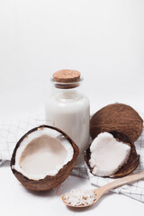 Coconut milk in a glass bottle. Whole and cracked coconut on white background