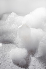 White shampoo bottle in and foam around. Abstract square background