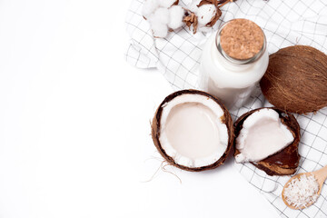 Coconut with coconut oil, water and sugar and coconut flakes on a wooden turquois background