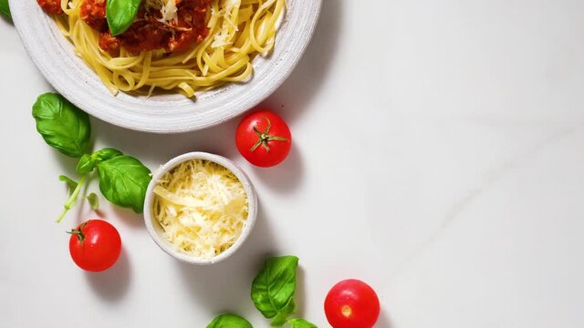 Italian pasta tagliatelle or spaghetti bolognese in a plate on white marble table with ingredients. top view. 4 k video. healthy food