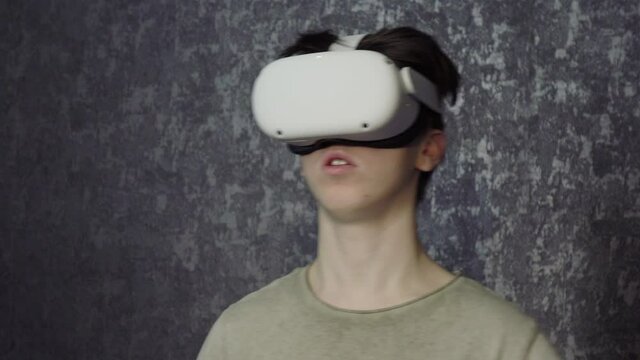 A teenager wearing virtual reality glasses .A young man uses a VR headset helmet to play games. View virtual reality videos . Technologies of the future.
