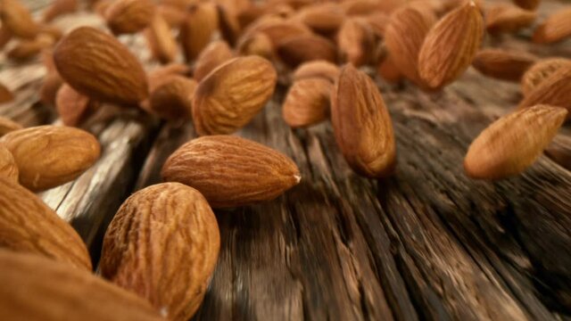 Super slow motion of rolling almonds on wood with camera motion. Filmed on high speed cinema camera, 1000fps.