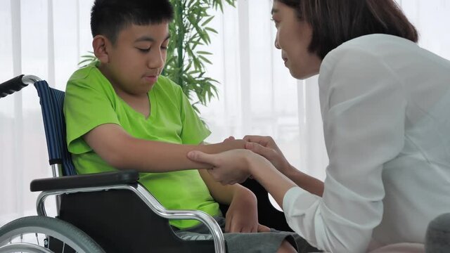 Mother holding hands boy with disability on wheelchair at home. Supportive, Encouragement, Care, Coexistence Slow motion shot