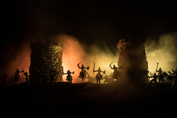 Fototapeta premium Medieval battle scene. Silhouettes of figures as separate objects, fight between warriors at night. Creative artwork decoration. Foggy background.