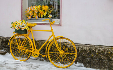 Fototapeta na wymiar Yellow bicycle stands on the background of the wall, under the window of the flower shop, vintage style