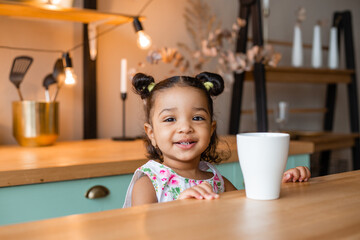 cute little african american girl at home in the kitchen