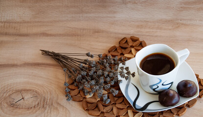 cup of espresso coffee, dry flowers and candies on wooden background