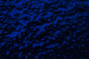 Abstract blue mysterious background. Rough texture in dark light. Oily, oily ooze with bubbles and lumps. Dark uneven background with reflected blue light. 3d illustration with gestural texture.