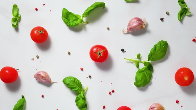 Tomatoes cherry, basil, garlic and pepper on white background. Top view. Cooking concept. Food composition. 4k rotates video. Italian food