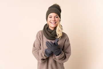 Young woman with winter hat over isolated background applauding