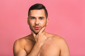 Fototapeta premium Photo of smiling young beautiful man standing isolated over pink wall background naked. Man's skincare concept in a bathroom.