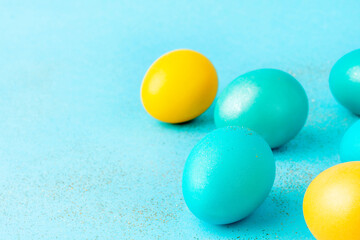 Traditionally painted Easter eggs on sparkling pastel azure background. Copy space.
