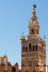 Giralda tower (La Giralda) a tall bell tower as part of the Seville Cathedral. The facade has Proverb 18 inscription close to the top. There are bronze bells , domes and a wind arrow at the very top.