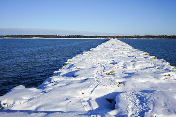 winter seascape, port entrance with snow covered concrete breakwater
