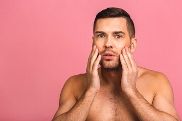 Obraz premium Photo of smiling young beautiful man standing isolated over pink wall background naked. Man's skincare concept in a bathroom.