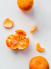 Top view of peeled and whole tangerine. Peel and pieces of citrus on white background. Ripe bright orange fruit.