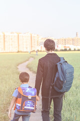 Brothers go to school. The teenager and his younger brother with backpacks hold hands, brothers...