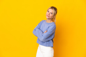 Young Russian woman isolated on yellow background with arms crossed and looking forward