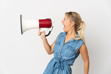 Young Russian woman isolated on white background shouting through a megaphone to announce something in lateral position