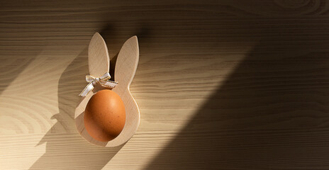 Easter breakfast on a wooden table: a boiled egg on a bunny stand - obrazy, fototapety, plakaty